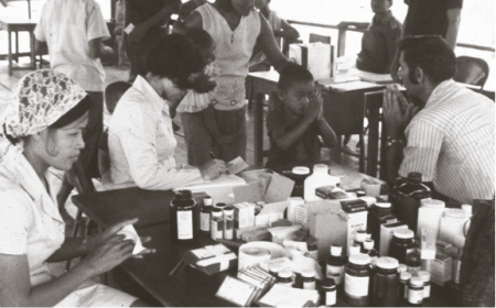 AFRIMS Captain Michael "Mike" Benenson (future USAMC director)  returns a “wai” while the study team prepares medications in the 1973 malaria drug prophylaxis study. (Photograph courtesy of Dr. Michael Benenson)